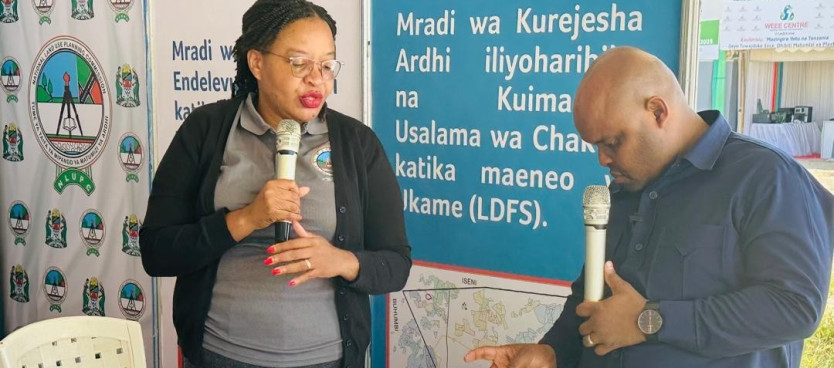 Msimamizi wa Ofisi ya Kanda ya Kati kutoka Tume  Bi. Suzana Mapunda akitoa maelezo juu ya Upangaji Matumizi ya Ardhi kwa Naibu Waziri Ofisi ya Makamu wa Rais (Muungano na Mazingira) Mhe. Khamis Hamza Khamis wakati wa Maadhimisho ya Siku ya Mazingira Dunia